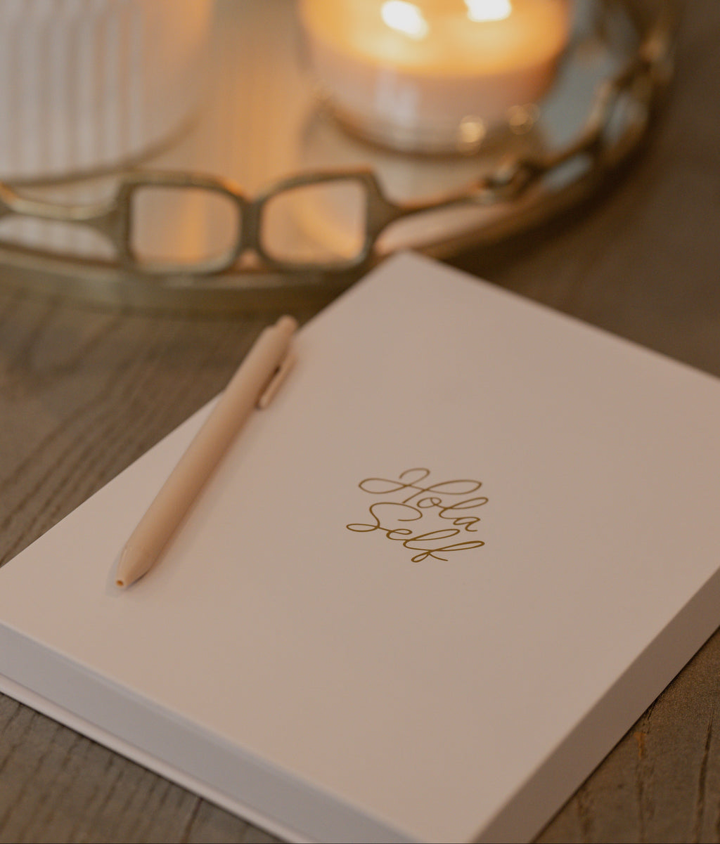 Notebook with a pen on a wooden surface with candles in the background